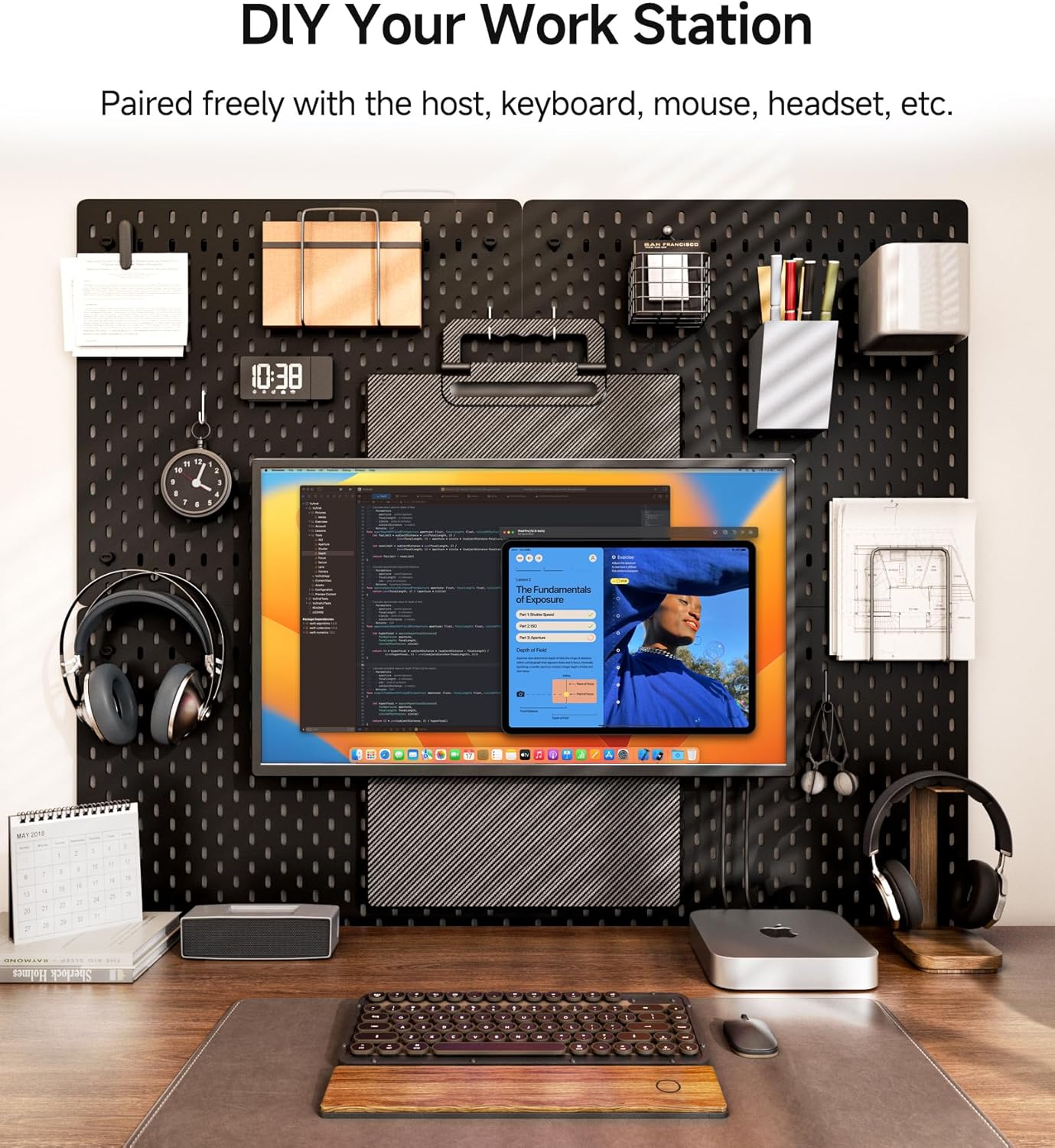 Desk setup with computer monitor, keyboard, and various office items against a pegboard wall.